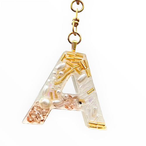 Letter 'A' pendant with gold accents and pearls on a white background