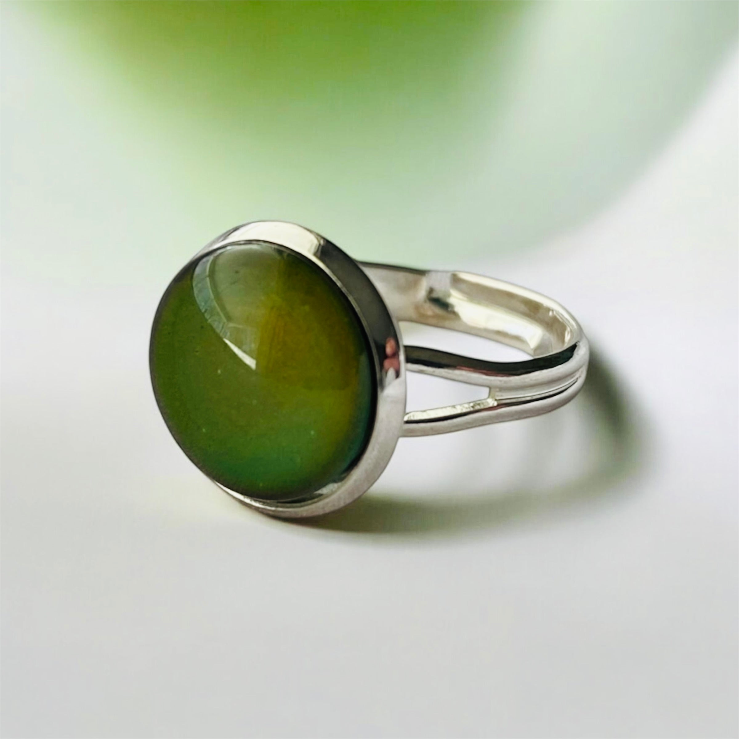 Mood Ring with olive-green stone and silver band, close-up.