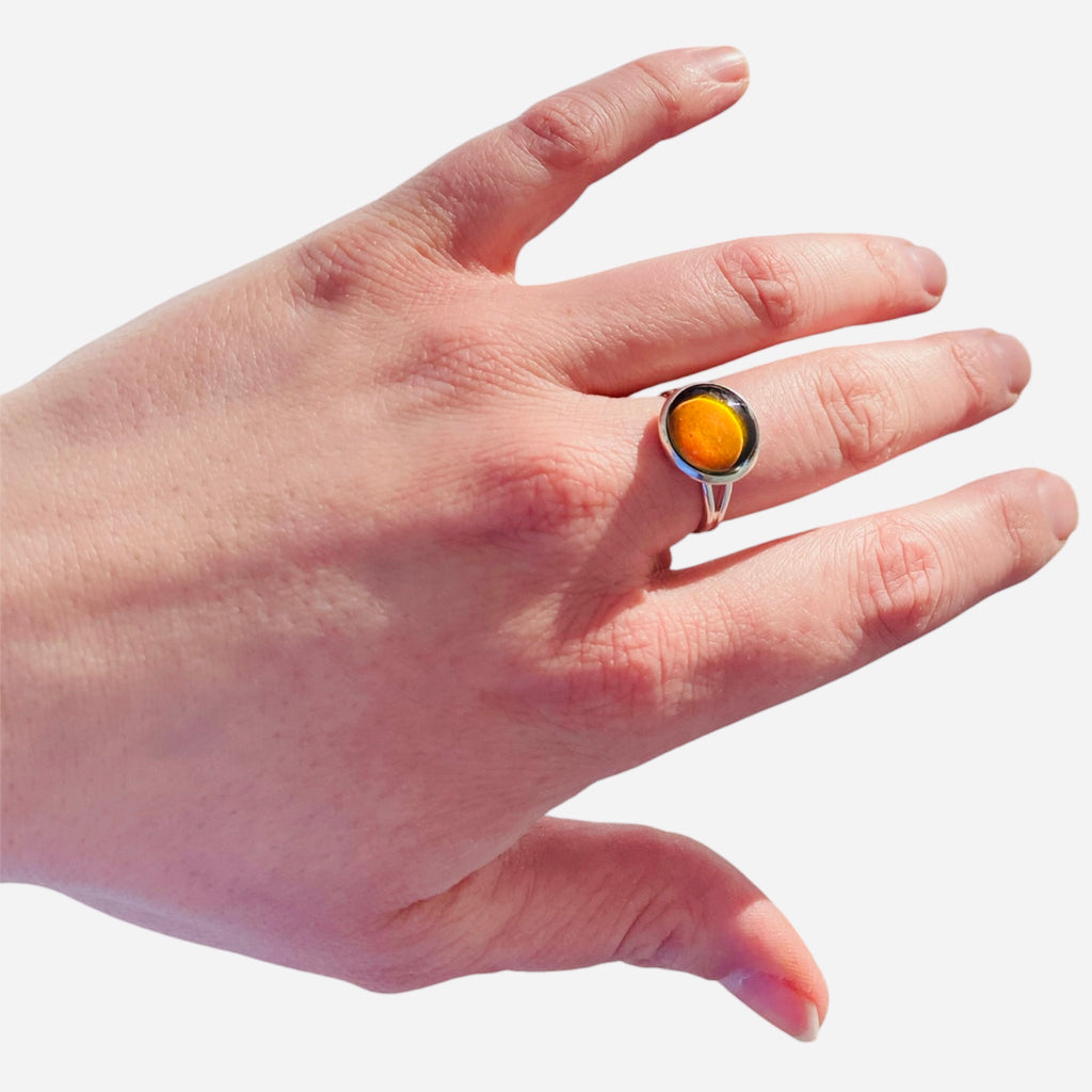 Mood Ring with orange amber gemstone on finger.