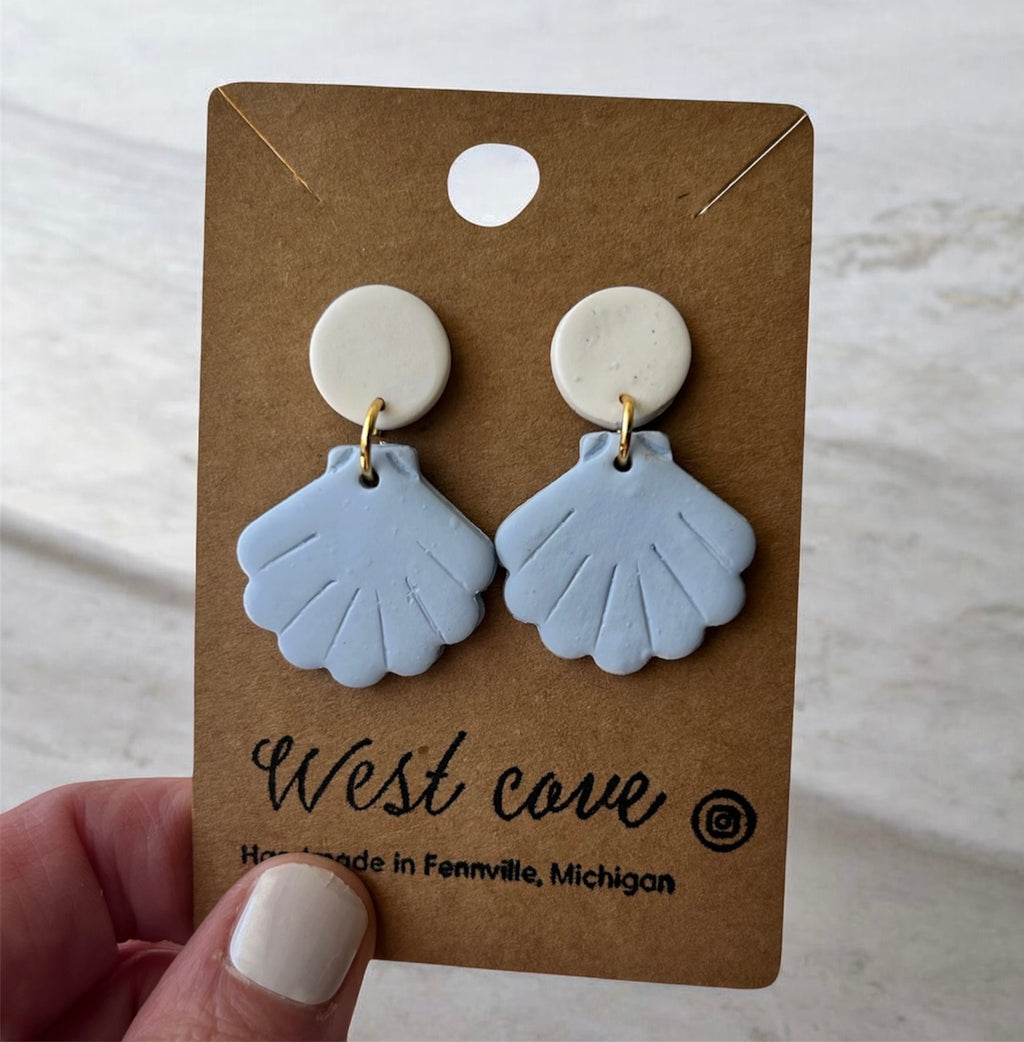 Handmade polymer clay earrings: blue sea shell dangles with beige studs on kraft card, coastal beachy style