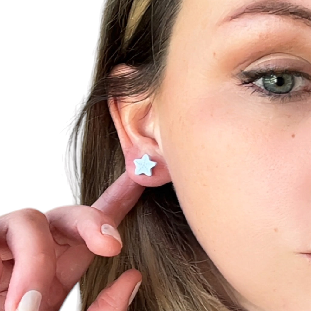 Light-blue polymer clay starfish stud earrings for hypoallergenic coastal beach jewelry.